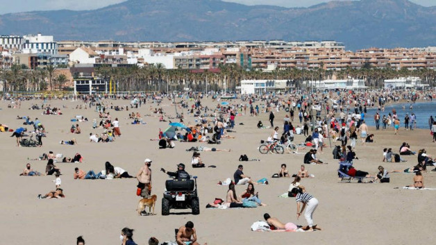 Miles de personas de personas en la playa de la malvarrosa y el aseo maritimo de valencia